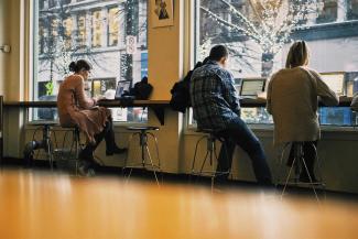 Millennials on laptops in coffee shop.